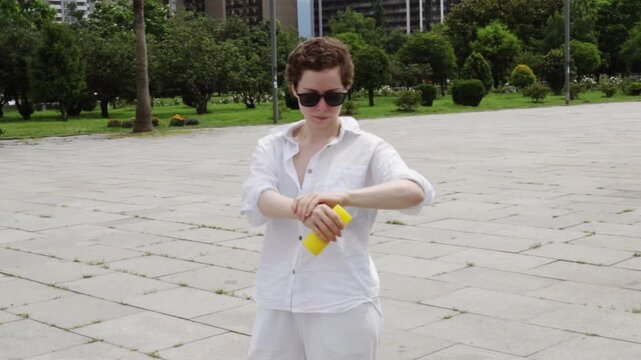 cancer survivor applies sunscreen in a modern urban setting, representing ultraviolet protection, skin sensitivity and confident life after oncology treatment in summer