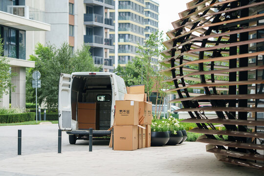Commercial delivery van parked on a city street with cardboard boxes stacked nearby