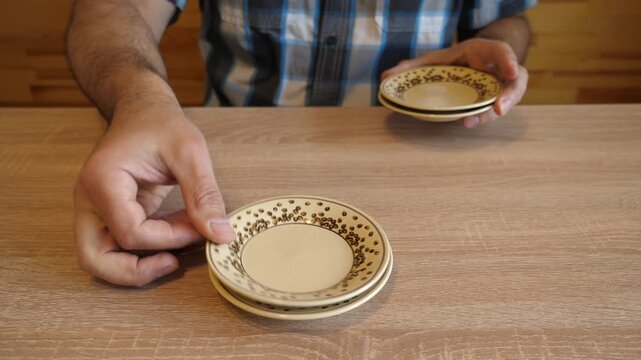 A person continuously stacks ceramic plates one on another, creating distinctive clicking sounds. The video contains original sound of ceramic.