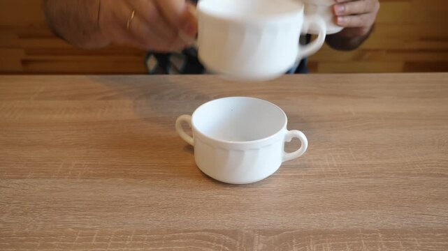 A person continuously stacks ceramic cups one on another, creating distinctive clicking sounds. The video contains original sound of ceramic.