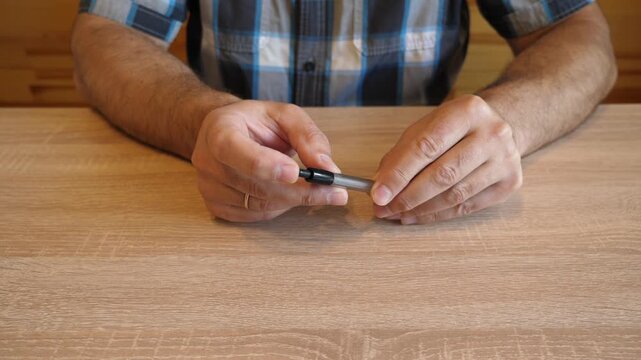 A person continuously presses the push button of a ballpoint pen, rhythmically clicking the mechanism. The video contains original sound of a pen click.