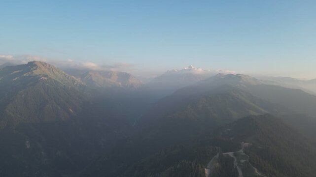 Wide aerial view of dark mountain ranges with a distant snow-capped peak.