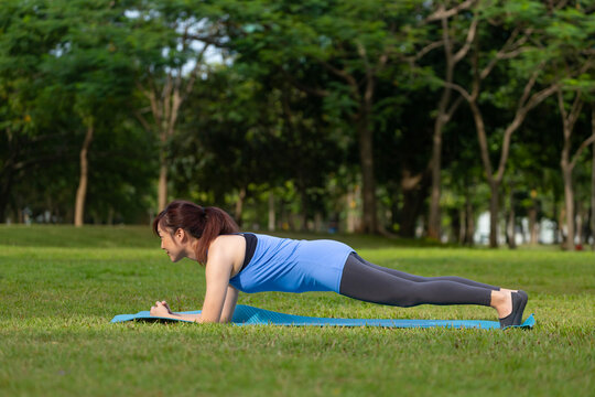 Asian woman relaxingly practicing planking for core muscle build after exercise inside the public park