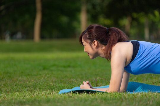 Asian woman relaxingly practicing planking for core muscle build after exercise inside public park