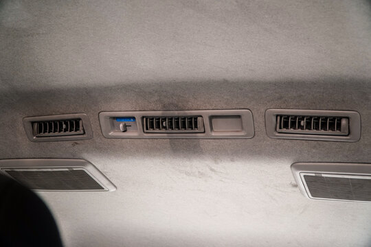 Close-up of car interior ceiling featuring air vents and climate control panel with textured gray fabric background. Modern automotive design detail for vehicle customization or tech-themed projects.