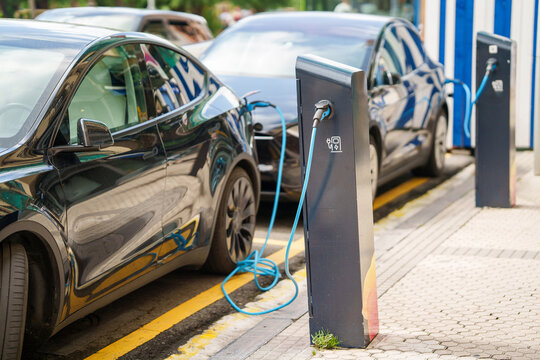Row of electric vehicles charging at a outdoor public EV station in the city