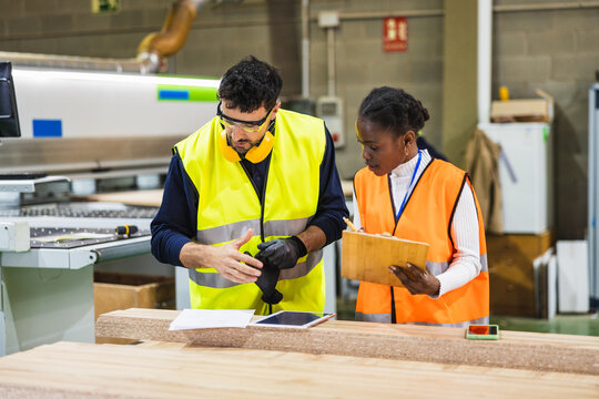 Multiracial workers collaborating in wood processing factory