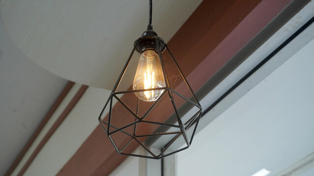 Modern geometric pendant lamp with edison bulb hanging from wooden ceiling beam.