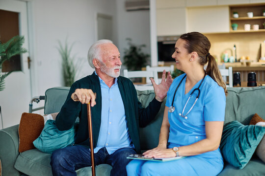 Doctor or nurse caregiver with senior man talking and having fun at home or nursing home