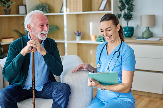 Doctor or nurse caregiver with senior man talking and having fun at home or nursing home