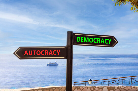 Democracy or autocracy words symbol. Concept words Democracy Autocracy on beautiful black road sign. Beautiful blue sky background. Business democracy autocracy concept. Copy space