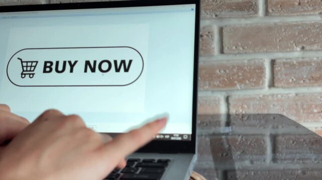 Female hands typing on a laptop keyboard and using the trackpad to move the cursor over a buy now button, symbolizing online shopping, e commerce, and digital transactions