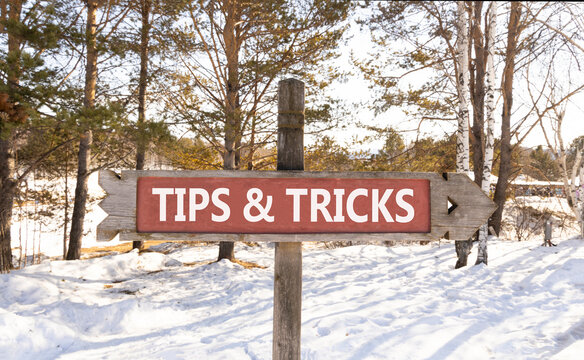 Tips and tricks words symbol. Concept words Tips and tricks on beautiful wooden road sign. Beautiful snow forest background. Business tips and tricks motivational support concept. Copy space.