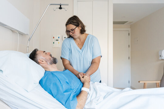 Wife supporting ill husband in hospital bed