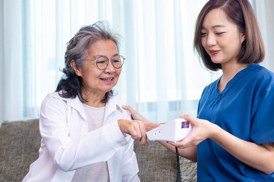 Senior woman got medical service visit from caregiver nurse at home while having result of medical exam from pulse oximeter for health care and pension welfare insurance