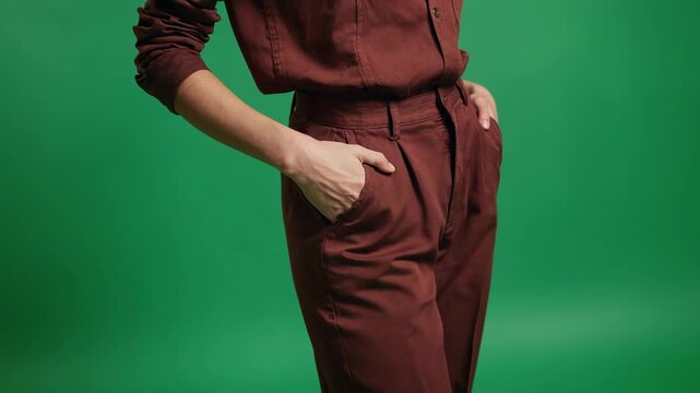Woman's maroon jumpsuit with hands in pockets against a green screen background seamless loop
