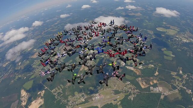 More than 100 skydivers together in a large formation.