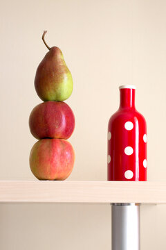 Still life with apples and pears and a red vase on a shelf