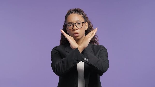 Serious african woman in glasses crossing hands to make clear stop gesture while looking at camera. School girl, college student or young professional expressing rejection, refusal, disagreement