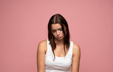 Obraz premium Unhappy young woman feeling sad and depressed, experiencing disappointment and negative emotions on pink background