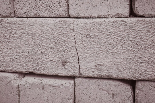 Cracked lightweight concrete block within a stacked masonry load, useful for defect inspection, quality control, structural damage, repair, and construction risk concepts.
