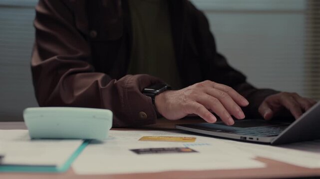 Person typing laptop keyboard reviewing financial documents' calculator credit card managing budget planning tax return business investment strategy analysis accounting commercial operation corporate.