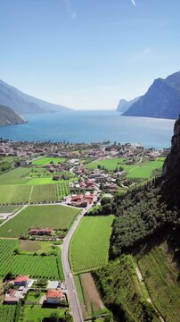 Wide drone shot of Torbole between water and cliffs on the edge of Lake Garda