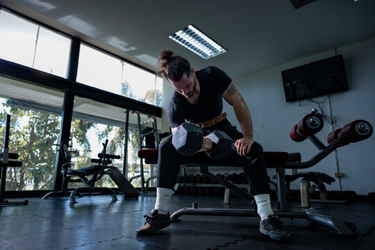 Caucasian man with strong and muscular body training on bent over row dumbbell with bench to build back and wing muscle