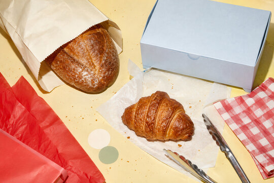Croissant and artisan bread in colorful bakery packaging