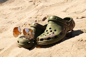 Sunglasses and beach slippers on the sand, themed around summer vacations in Ukraine, holidays, beaches, heat © Виктория Котлярчук