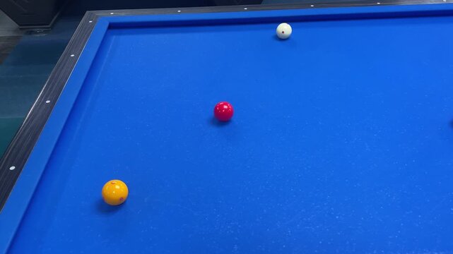 Carom billiards game with four balls on blue felt table with cue stick