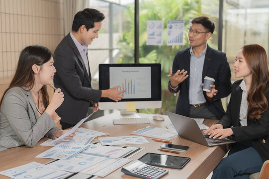 Group of serious Asian business people analyzing financial charts in office meeting.