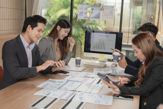 Group of serious Asian business people analyzing financial charts in office meeting.