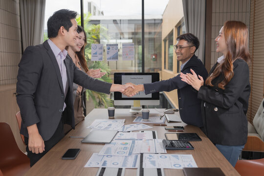 Group of diverse Asian business people stacking hands together in office meeting.