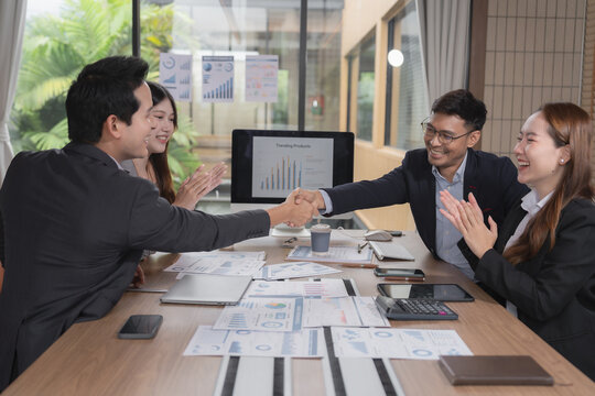 Group of diverse Asian business people stacking hands together in office meeting.