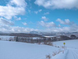 Snow-covered mountain landscape beneath a blue sky with drifting clouds © seunghoo