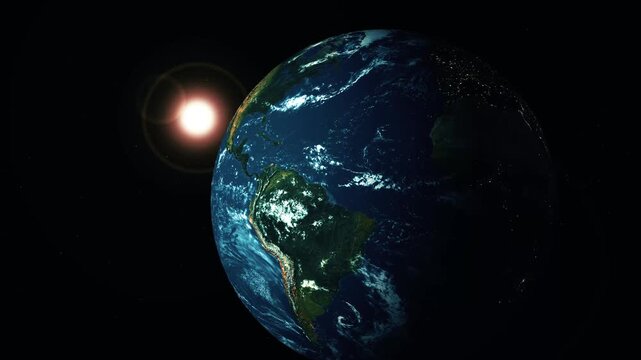 Planet earth in space with sunlight, visible continents and clouds, half in shadow against a black background.