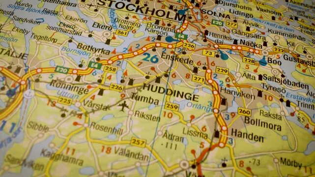 macro flight to stockholm, sweden, across detailed road atlas map