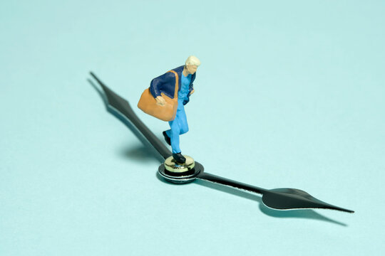 Miniature tiny people toy figure photography. A women running above black clockwise carrying duffle bag. Isolated on blue background