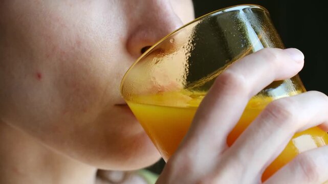 Close up young woman mouth drinks fresh orange juice from glass, savoring healthy refreshing taste for breakfast. Healthy lifestyle, vitamin intake concept. Woman drinking fresh orange juice close up