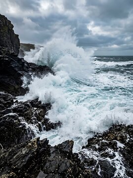 Powerful ocean waves crashing against rocky cliff.