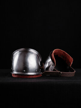 Interior view of steel pauldrons showing soft lining, riveted plates, and adjustable leather straps, photographed against a black backdrop.