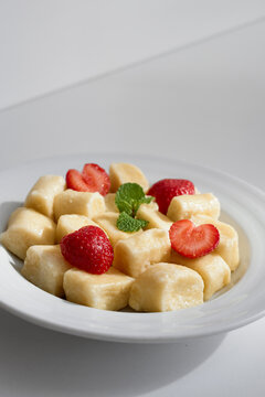 Creamy cheese cubes paired with fresh strawberries and mint on a white plate. A light, elegant dessert or snack with bright colors and a refreshing, gourmet presentation.