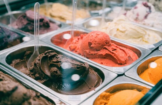 Assorted colorful artisanal gelato scoops displayed in metal containers at an ice cream shop
