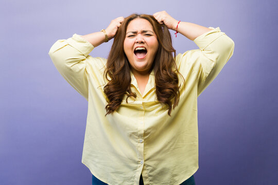 Stressed woman screaming in frustration, pulling her hair, showing emotional outburst and mental health struggle