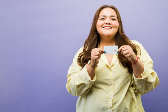 Cheerful plus size woman showing blank credit card, promoting financial services and secure online shopping