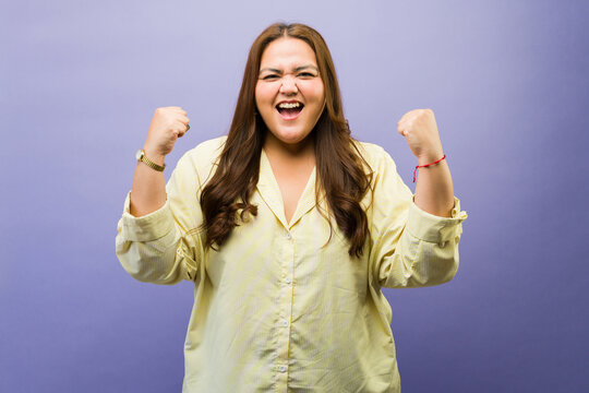 Plus size woman celebrating success, screaming with excitement, achieving victory, showing happiness
