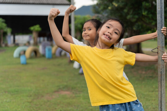 Happy children posing and playing outdoors on a school playground beside a spinning pole. Smiling friends enjoying active play, friendship, childhood, teamwork, healthy lifestyle and joyful recreation
