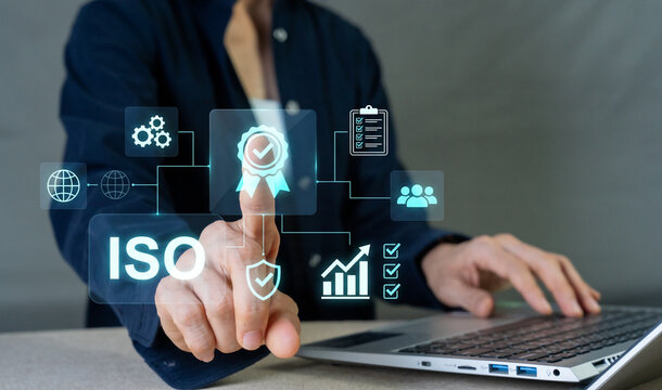 Businessman pressing ISO certification icon with laptop for quality management standard and compliance