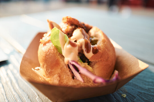 Gourmet slider with slaw and sauce on a blue picnic table